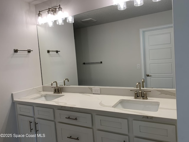 bathroom with double vanity, visible vents, and a sink