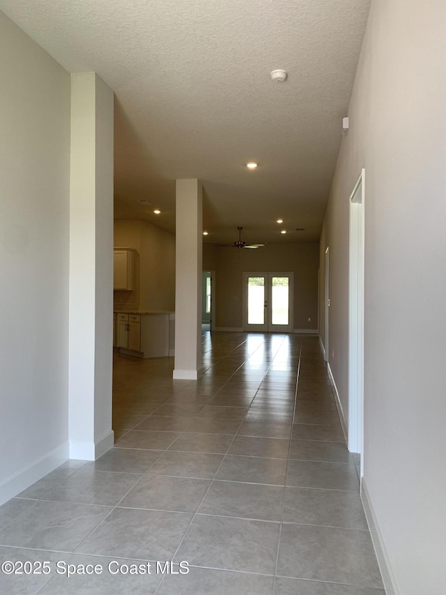 corridor featuring light tile patterned floors, baseboards, recessed lighting, and a textured ceiling