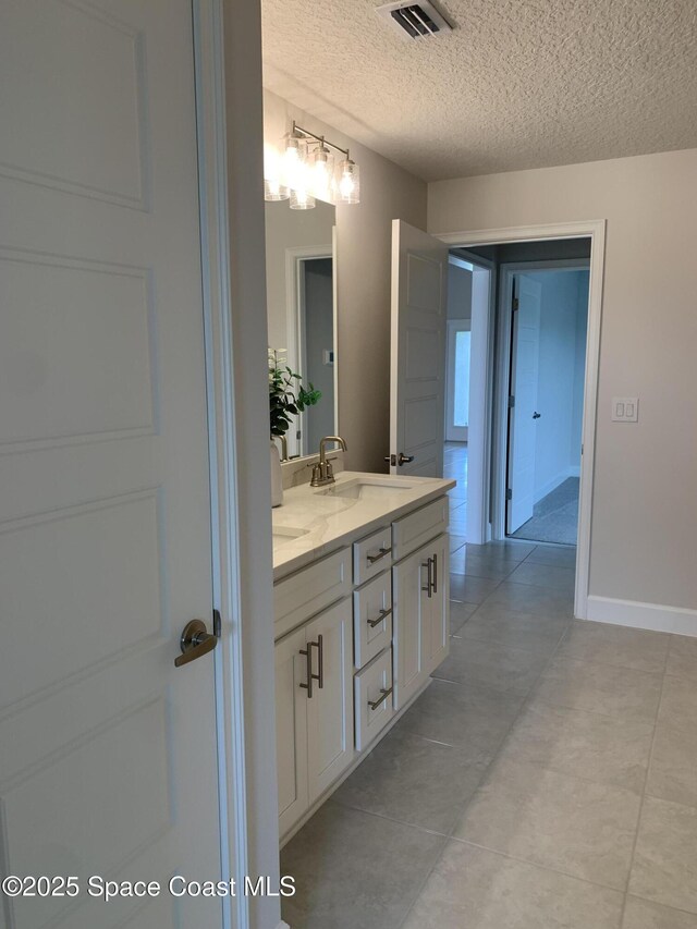full bath featuring a sink, double vanity, a textured ceiling, tile patterned floors, and visible vents