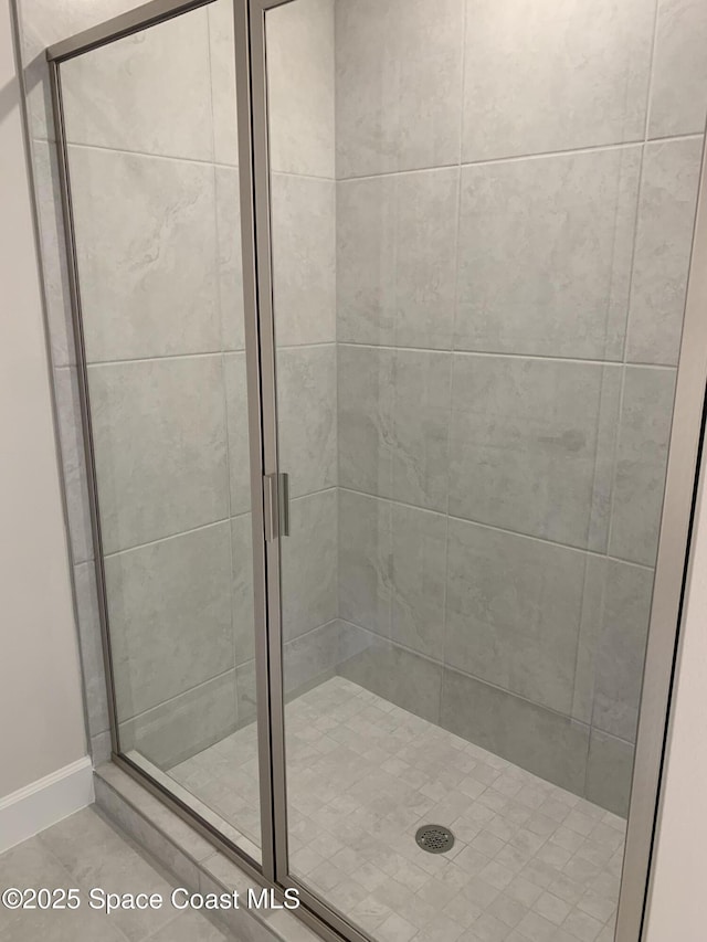 bathroom featuring baseboards, tile patterned flooring, and a stall shower