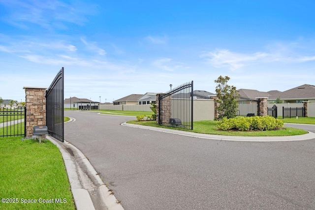 view of street featuring a residential view, a gate, and curbs