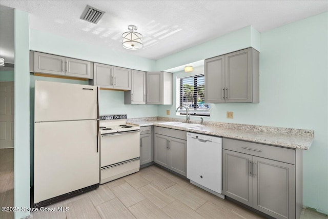 kitchen with gray cabinetry, a sink, and white appliances