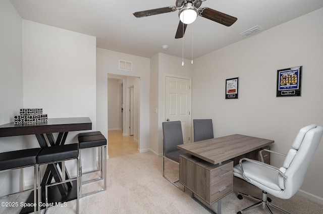office space featuring light colored carpet, ceiling fan, baseboards, and visible vents