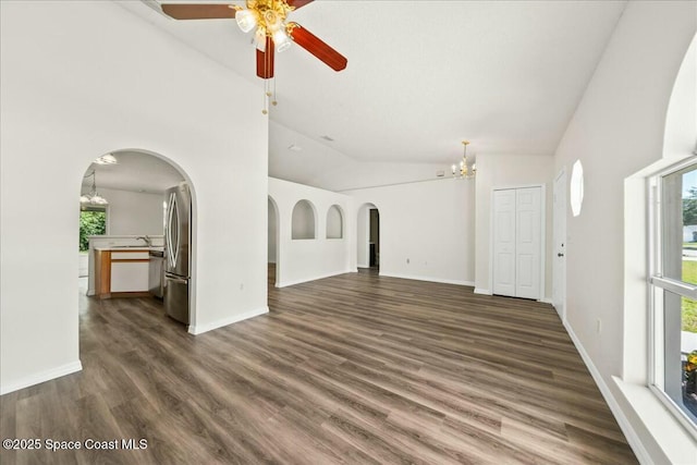 unfurnished living room featuring dark wood-type flooring, arched walkways, plenty of natural light, and lofted ceiling