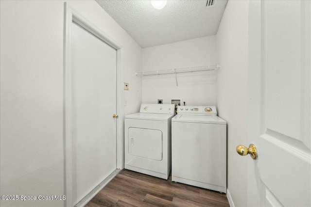 clothes washing area featuring independent washer and dryer, dark wood-type flooring, laundry area, and a textured ceiling