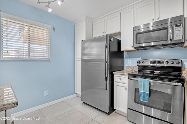 3150 N Harbor City Blvd Unit 236, Melbourne, FL 32935 - kitchen featuring baseboards, light stone counters, light tile patterned flooring, white cabinets, and stainless steel appliances