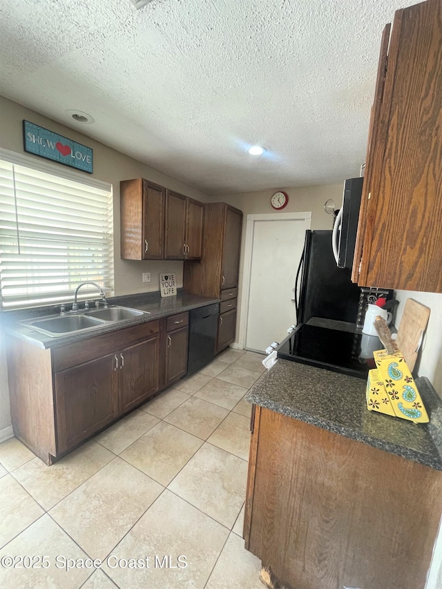 kitchen with dark countertops, a sink, a textured ceiling, and black appliances