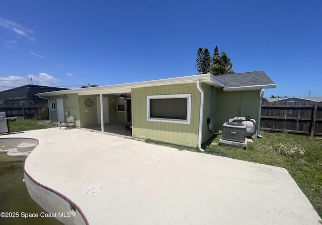back of property featuring a shingled roof, a patio, and fence
