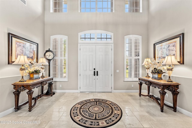entryway featuring baseboards, a high ceiling, and stone tile flooring
