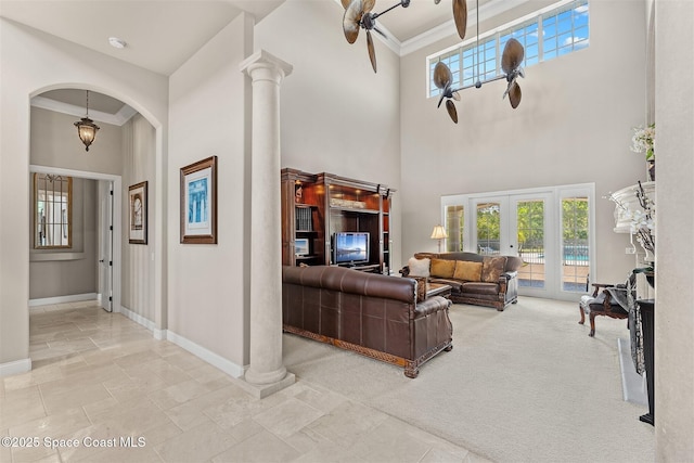 living area featuring arched walkways, baseboards, a high ceiling, a ceiling fan, and ornamental molding