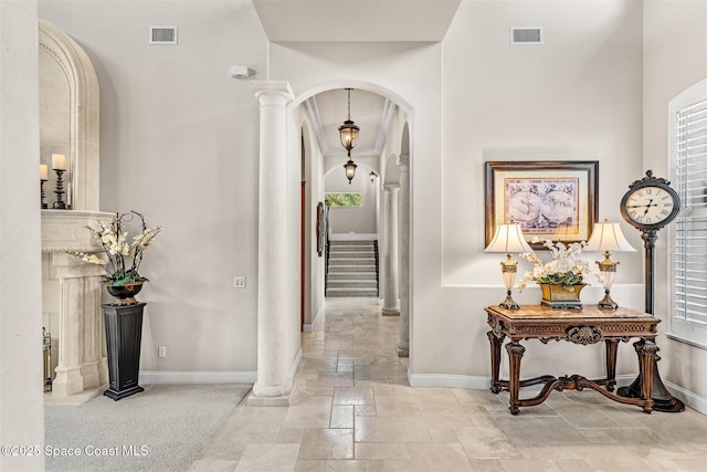 corridor with stone tile flooring, baseboards, ornate columns, and arched walkways