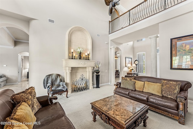 living room with arched walkways, a towering ceiling, carpet, baseboards, and ornate columns