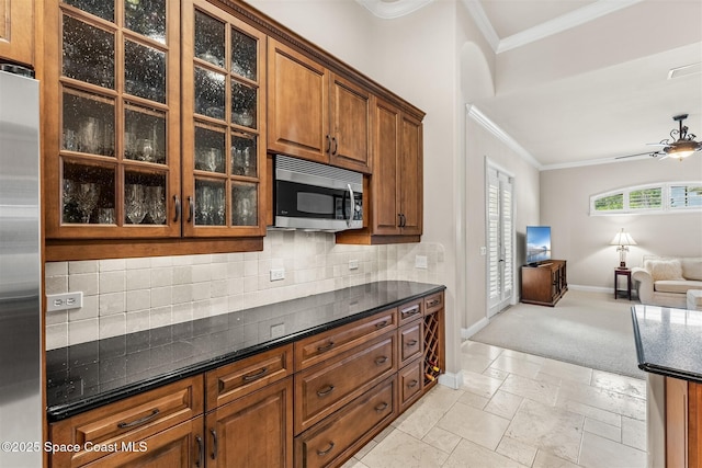 kitchen featuring appliances with stainless steel finishes, ornamental molding, open floor plan, tasteful backsplash, and baseboards