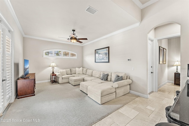 living room featuring a ceiling fan, baseboards, arched walkways, stone tile floors, and crown molding
