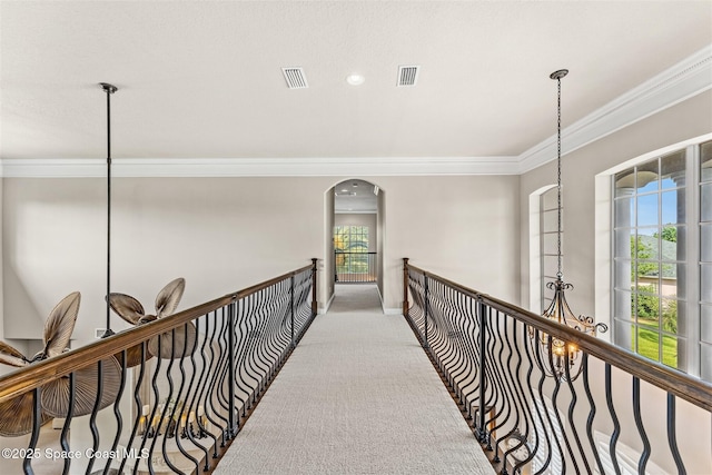 hallway with ornamental molding, carpet floors, arched walkways, and baseboards