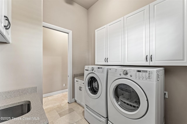 washroom with washer and clothes dryer, cabinet space, stone tile floors, and baseboards