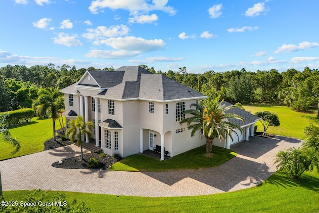 back of property with decorative driveway, a yard, stucco siding, and french doors