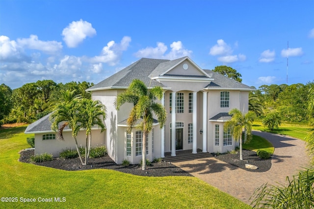 neoclassical home featuring a front lawn and stucco siding