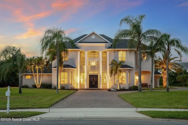 view of front of home with driveway, a front lawn, and stucco siding
