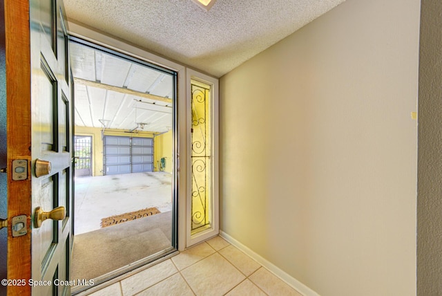 doorway featuring a textured ceiling, light tile patterned floors, and baseboards