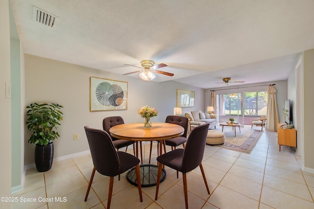 dining room with light tile patterned floors, visible vents, baseboards, and a ceiling fan