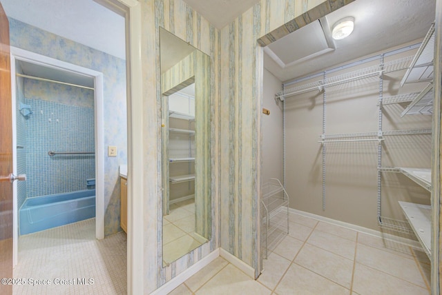 full bathroom with tile patterned floors, a walk in closet, baseboards, and wallpapered walls