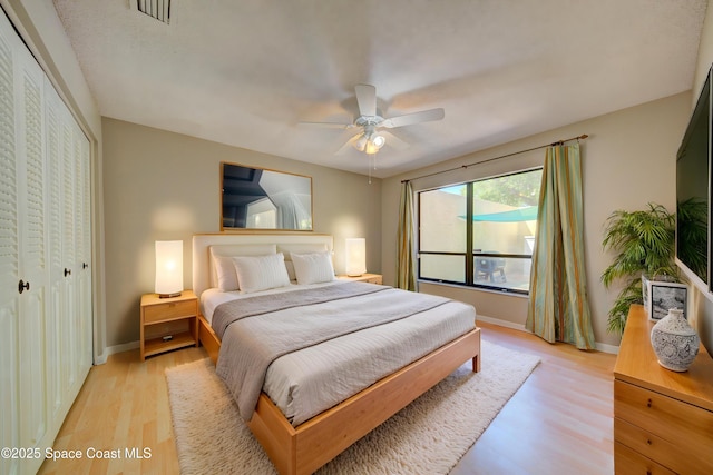bedroom featuring a closet, baseboards, a ceiling fan, visible vents, and light wood finished floors