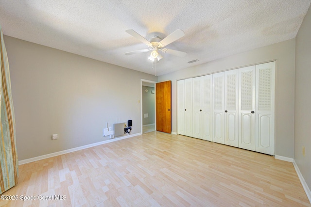 unfurnished bedroom featuring visible vents, baseboards, ceiling fan, a textured ceiling, and light wood-style flooring