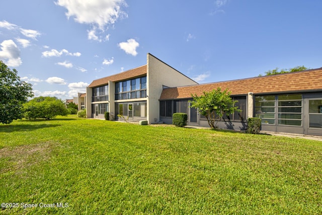 back of house with a lawn and stucco siding