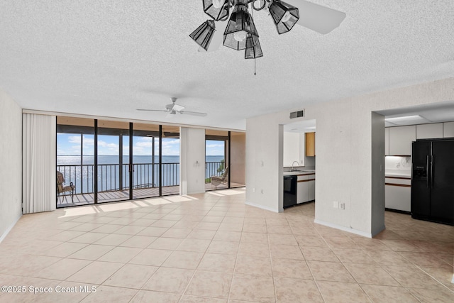 5801 N Banana River Blvd Unit 936, Cape Canaveral, FL 32920 - unfurnished living room featuring a water view, visible vents, a ceiling fan, a textured ceiling, and floor to ceiling windows