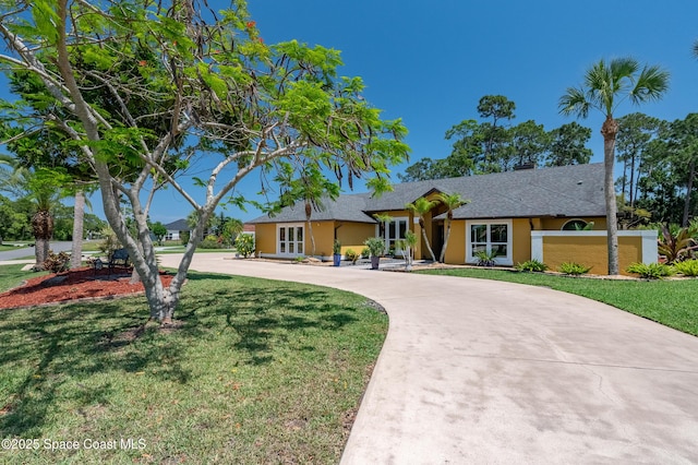 ranch-style house featuring curved driveway, a shingled roof, a front lawn, and stucco siding