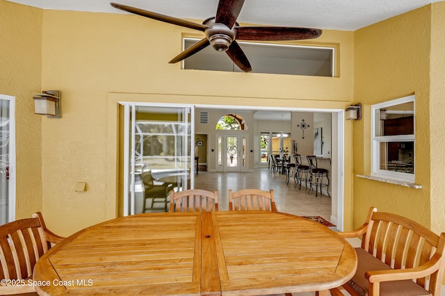 dining space featuring a ceiling fan and a textured wall