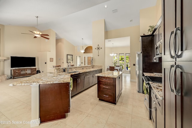 kitchen with lofted ceiling, dark brown cabinetry, open floor plan, a ceiling fan, and appliances with stainless steel finishes