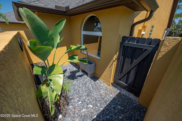 exterior space with a shingled roof, fence, stucco siding, and gutters