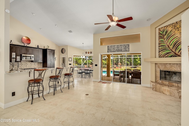 living area with baseboards, plenty of natural light, a ceiling fan, and lofted ceiling