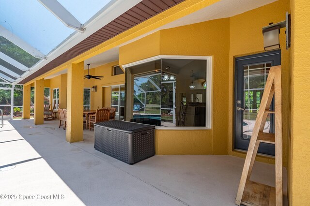 view of patio / terrace featuring glass enclosure, a ceiling fan, and outdoor dining area