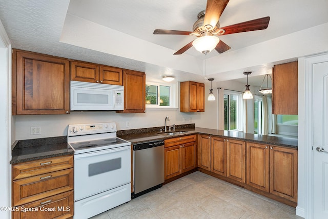 kitchen with white appliances, brown cabinetry, a sink, a ceiling fan, and light tile patterned flooring