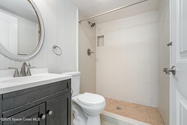 bathroom featuring vanity, toilet, tiled shower, and tile patterned flooring