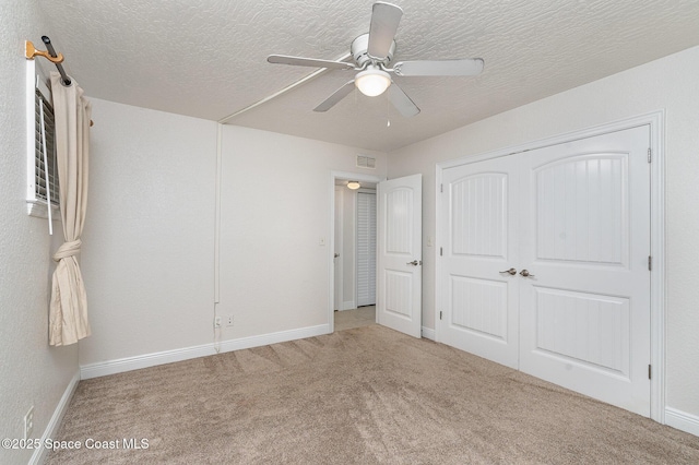unfurnished bedroom with carpet flooring, a textured ceiling, a closet, baseboards, and ceiling fan
