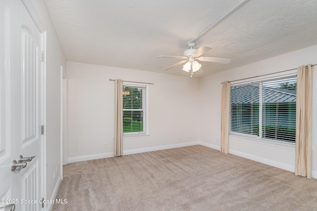 unfurnished room with a textured ceiling, a ceiling fan, light carpet, and baseboards