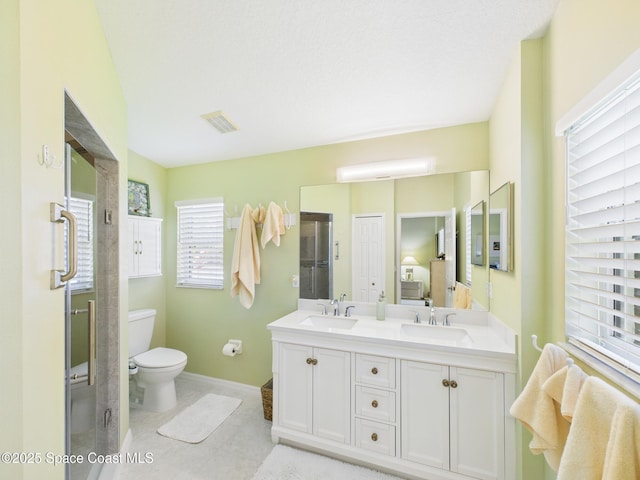 bathroom featuring visible vents, a sink, double vanity, and toilet