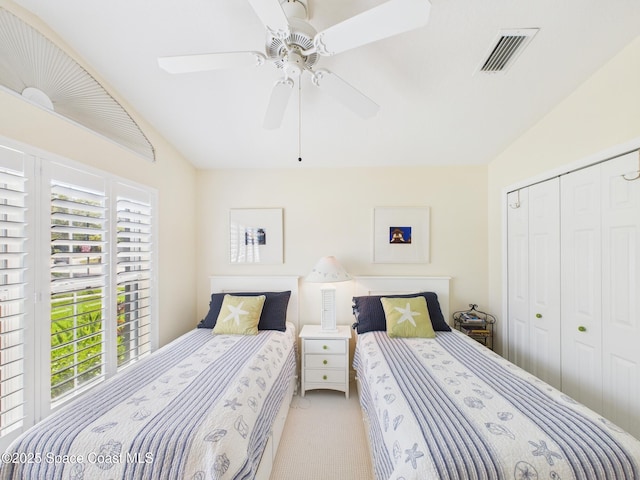 carpeted bedroom with ceiling fan, vaulted ceiling, visible vents, and a closet