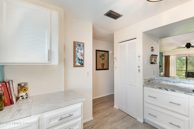 2245 Golf Isle Dr Unit 424, Melbourne, FL 32935 - kitchen with white cabinets, light wood-type flooring, baseboards, visible vents, and ceiling fan