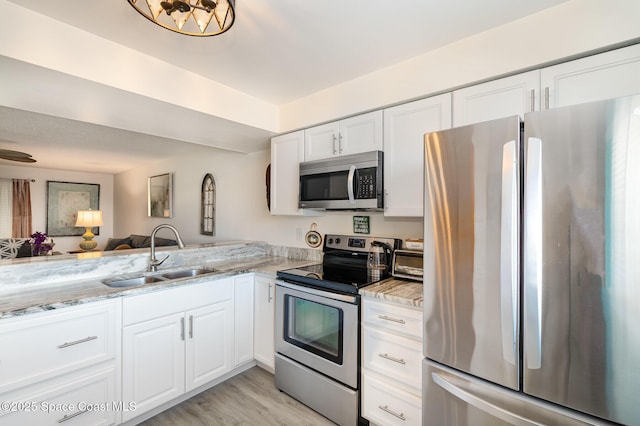 2245 Golf Isle Dr Unit 424, Melbourne, FL 32935 - kitchen featuring white cabinets, light stone counters, stainless steel appliances, a sink, and light wood-style floors
