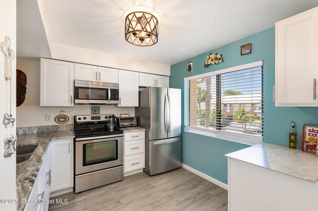 2245 Golf Isle Dr Unit 424, Melbourne, FL 32935 - kitchen with light wood finished floors, stainless steel appliances, a sink, and white cabinetry