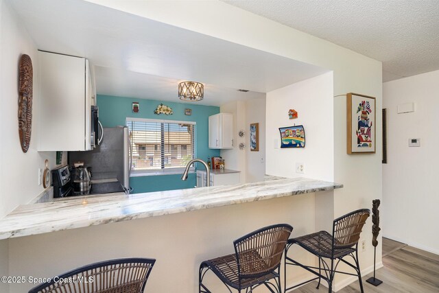 2245 Golf Isle Dr Unit 424, Melbourne, FL 32935 - kitchen with a sink, range with electric cooktop, stainless steel microwave, a peninsula, and white cabinetry