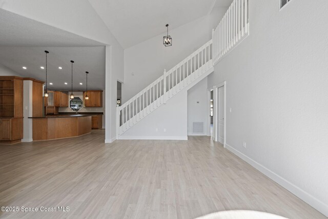 4000 Ocala St, Cocoa, FL 32926 - unfurnished living room featuring baseboards, stairway, light wood finished floors, and high vaulted ceiling