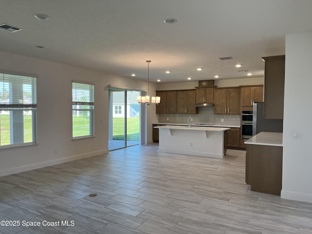kitchen featuring tasteful backsplash, visible vents, open floor plan, light countertops, and a chandelier
