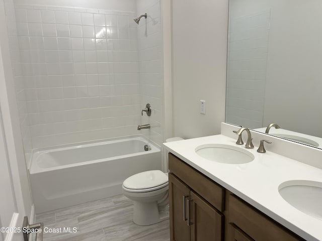 bathroom featuring double vanity,  shower combination, a sink, and toilet
