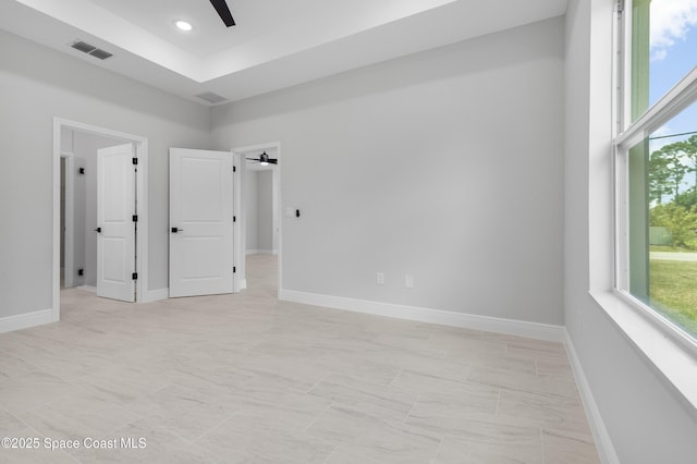 unfurnished bedroom featuring baseboards, multiple windows, and visible vents